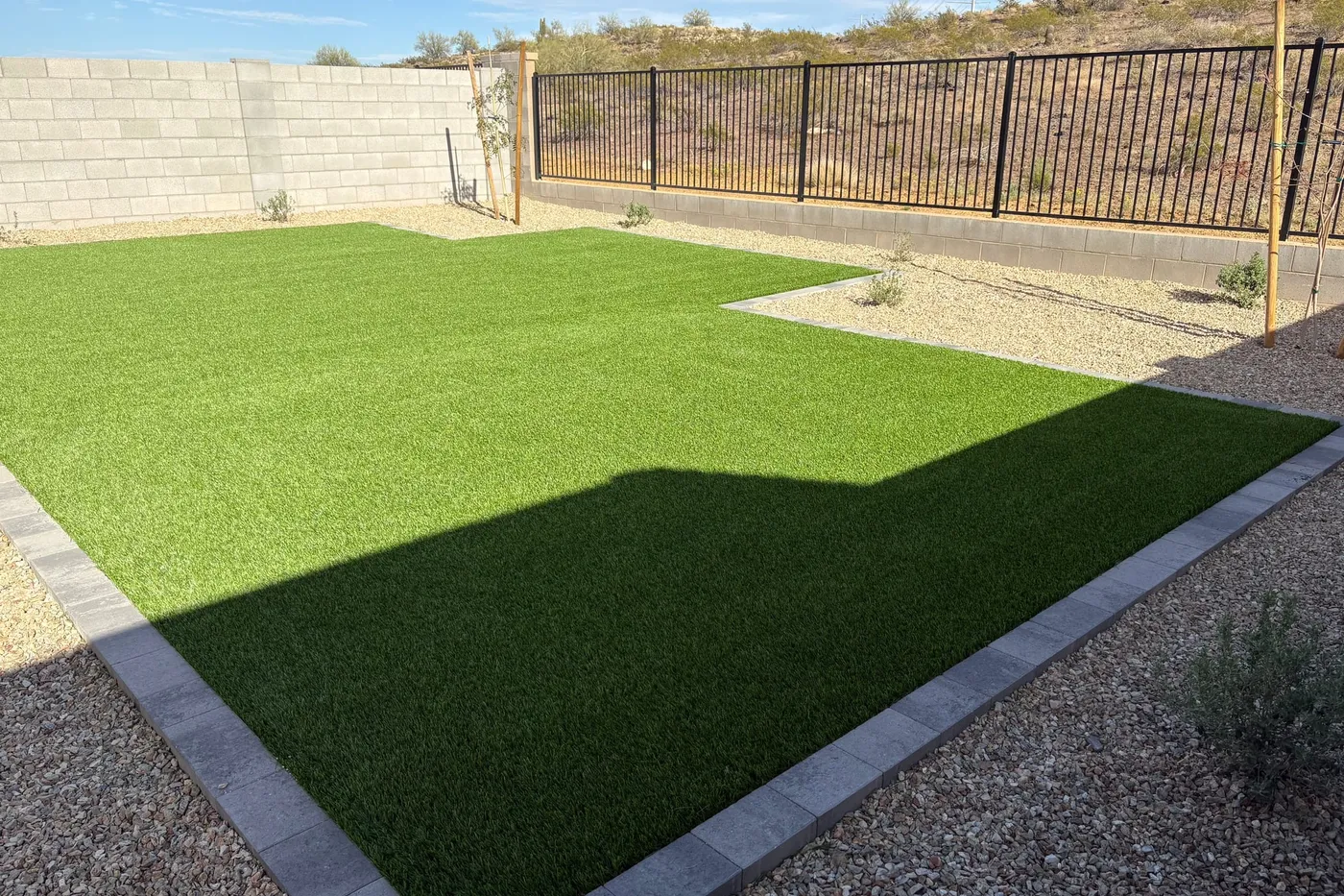 A backyard of artificial turf inside a block wall
